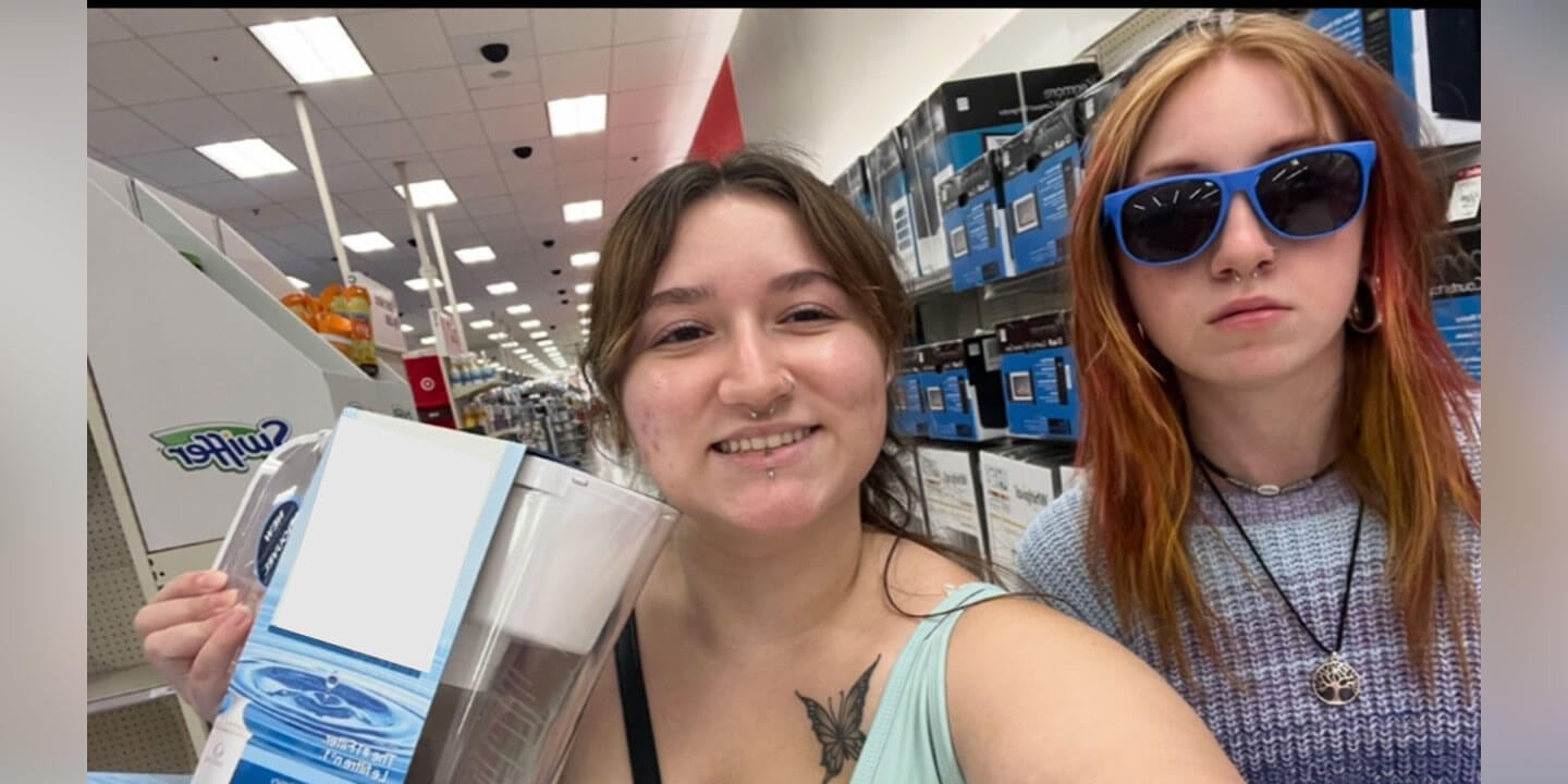 Two college women in a store aisle shopping for room accessories.