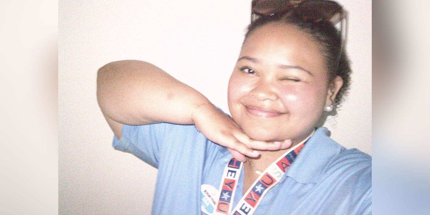 Selfie of a winking and smiling person wearing a light blue polo and lanyard.