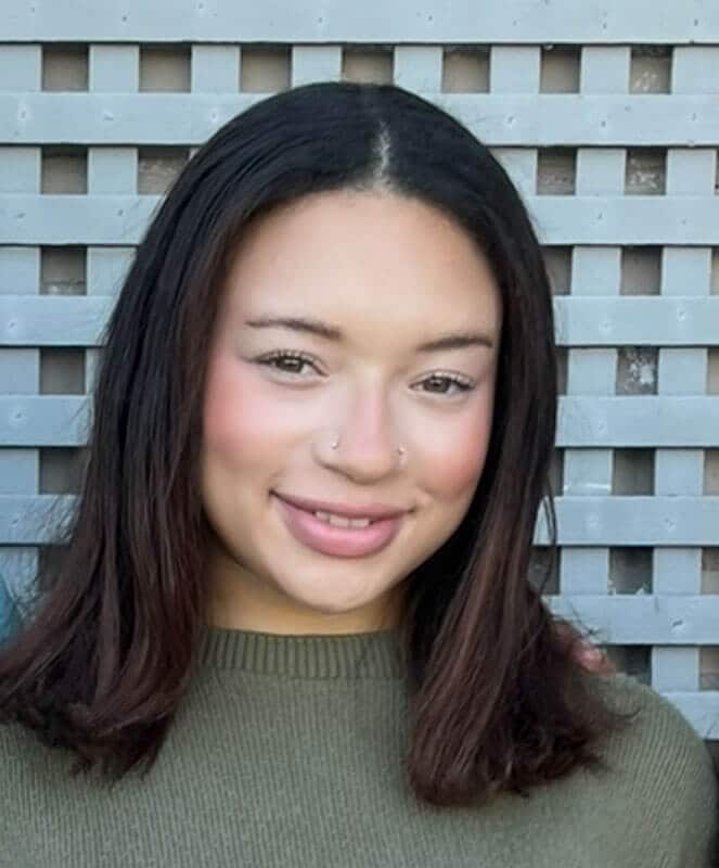 The blog author has dark hair and is wearing an olive green sweater in front of a lattice work background