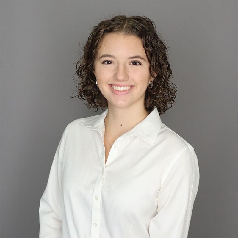 The blog author, Olivia, has medium-length curly brown hair and is wearing a white blouse with buttons down the front.