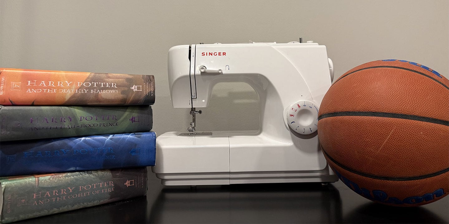 Image shows a stack of four Harry Potter books, a sewing machine and a basketball sitting on a table.