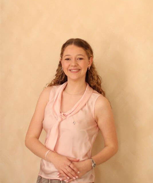 The blog author is standing outside with her hair pulled back. She is wearing a pink strapless dress.