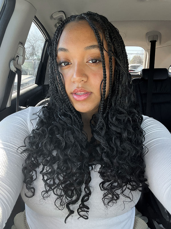 The blog author, Sarai, has long dark curly hair styled in braids and is wearing a white ribbed top.