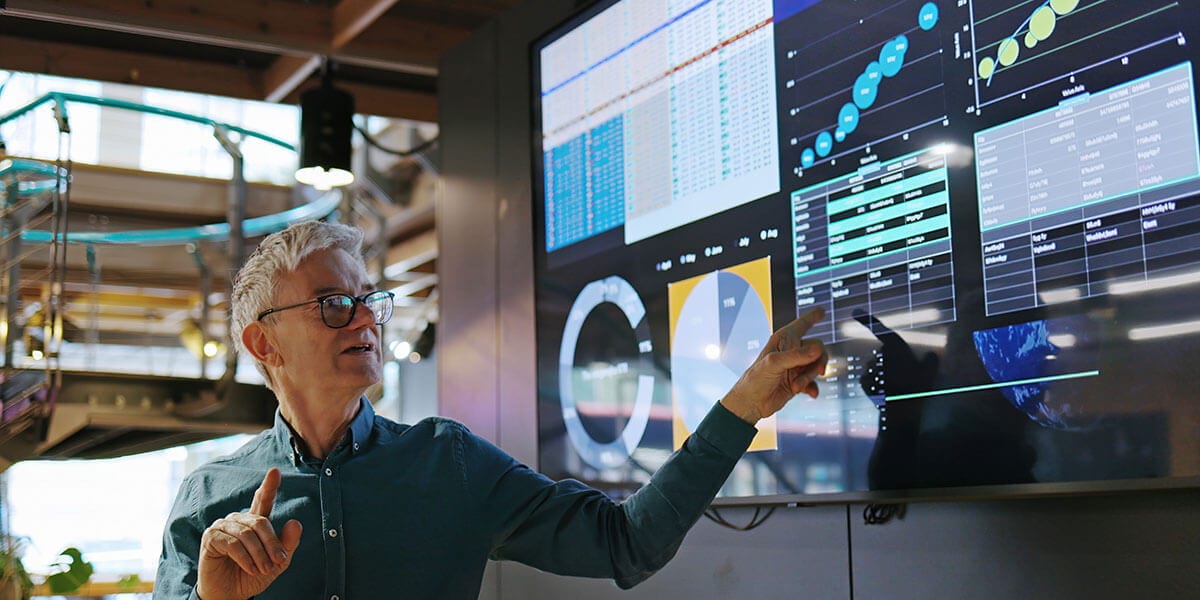 Man pointing out information on a quadrant IT monitor