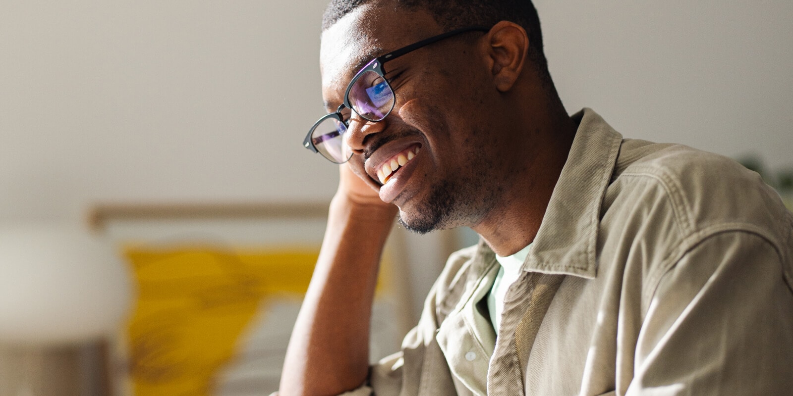 A smiling man rests his head in his hand