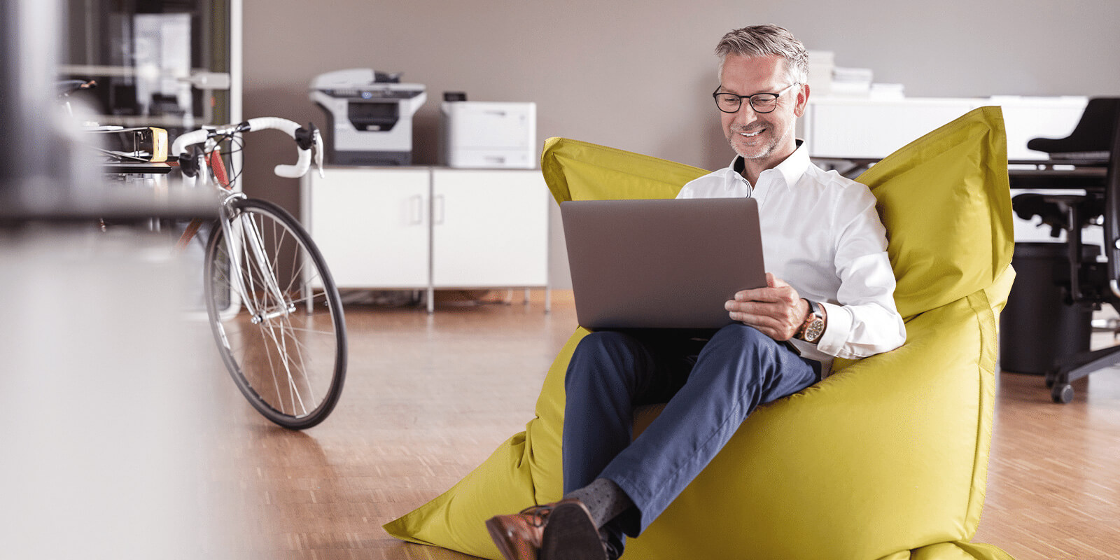 Man sitting in chair, smiling, as he is reviewing content on his laptop