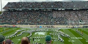 A view of a football game at Michigan State. The marching band is on the field.