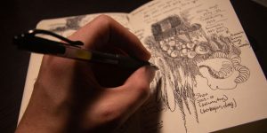 A close-up of someone’s hand drawing in a sketchbook.