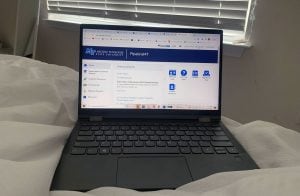 An open laptop on a bed. The screen is opened to a college webpage.