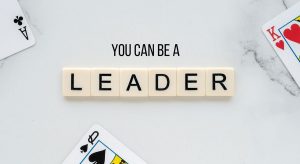 A computer generated graphic with 3 playing cards – an ace, queen, and king – and the words ‘You Can Be a Leader’. The word ‘leader’ is spelled out in Scrabble tiles.