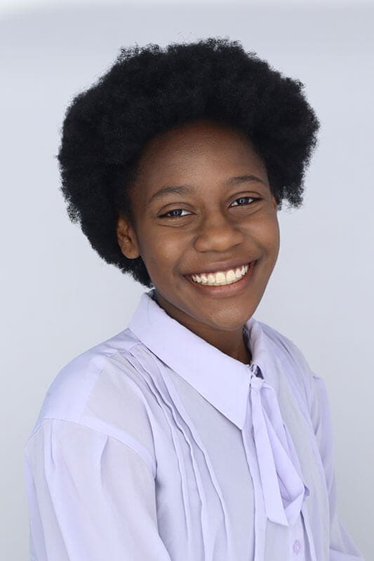 Blog author Jordan has a medium length afro and is wearing a light purple long sleeved blouse.