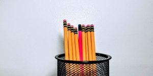 Nine pencils in a pencil cup. Eight of the pencils are the standard dark yellow color, but the one in the middle is hot pink.