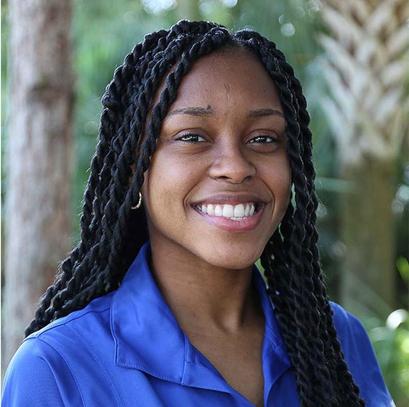 Blog author Kerri-Ann Henry is smiling, wearing a blue collared polo shirt. She has long, thick black braids.