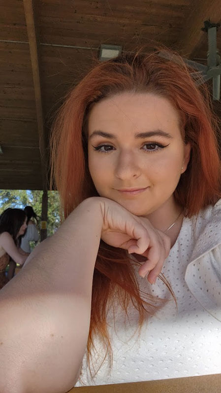 Blog author Kayleigh has long red hair and is leaning on her elbow with her chin in her hand.