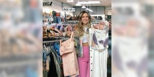 Blog author Logan Collins stands by a rack of clothes at her favorite local thrift store.