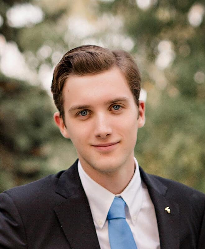 Blog author McKinley Falkowski is a white male college student with short brown hair and blue eyes. In this profile picture he is wearing a blue sport coat, white shirt, and light blue tie. The background behind him is blurred.