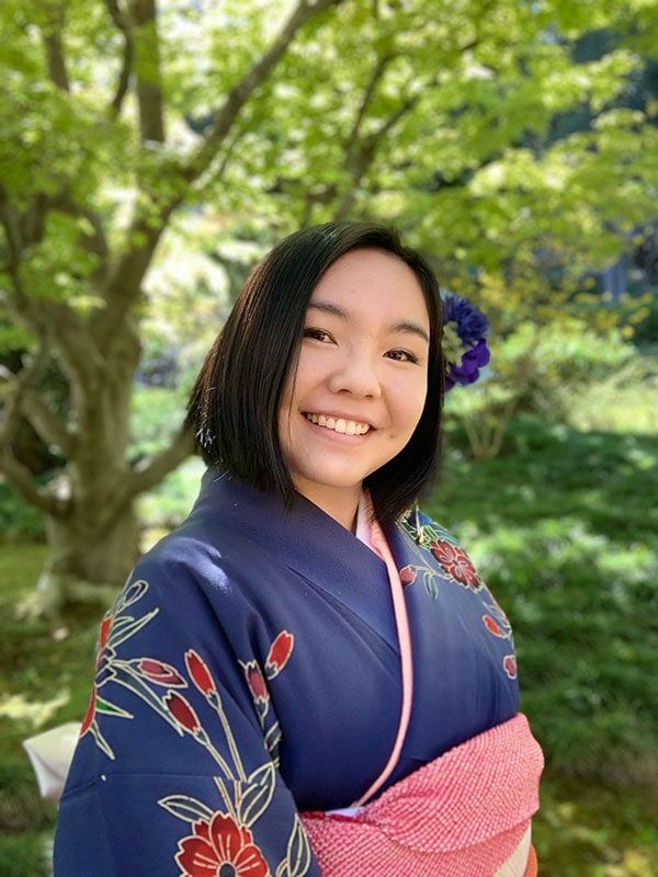 Blog author Miyu Nakajima is wearing a traditional kimono that is dark blue with a red sash at the waist.