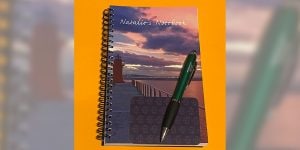A spiral notebook with the words ‘Natalie’s Notebook’ printed on the cover. A pen is placed on top of the notebook.