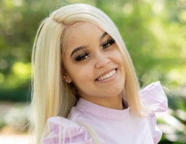 Blog author Nia LaCour is outside with trees behind her. She has long blonde hair and is wearing a pink blouse with puffy sleeves.