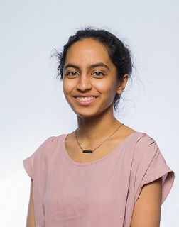 In this studio photo, blog author Rukmini Waranashiwar has her dark hair pulled back in a bun and is wearing a pink short-sleeved shirt.
