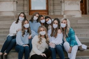 Blog author Sarah Faust sits with seven of her sorority sisters on the steps of an academic building. Due to quarantine rules, they are wearing facemasks.
