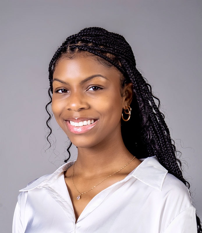 Professional headshot of blog author Taylor King. She has long black braids pulled half back and she is wearing a white blouse.