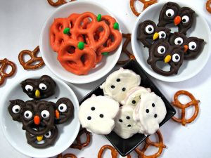 Four bowls of chocolate-covered pretzels decorated in orange, brown, and white colors.