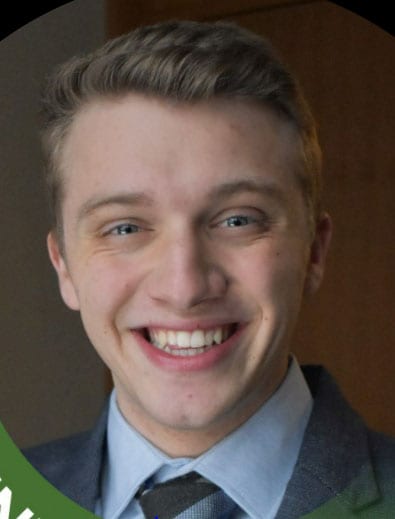 Blog author Zach Suozzo is has blonde hair and is smiling at the camera. He is wearing a dark suit coat, light color shirt, and tie.