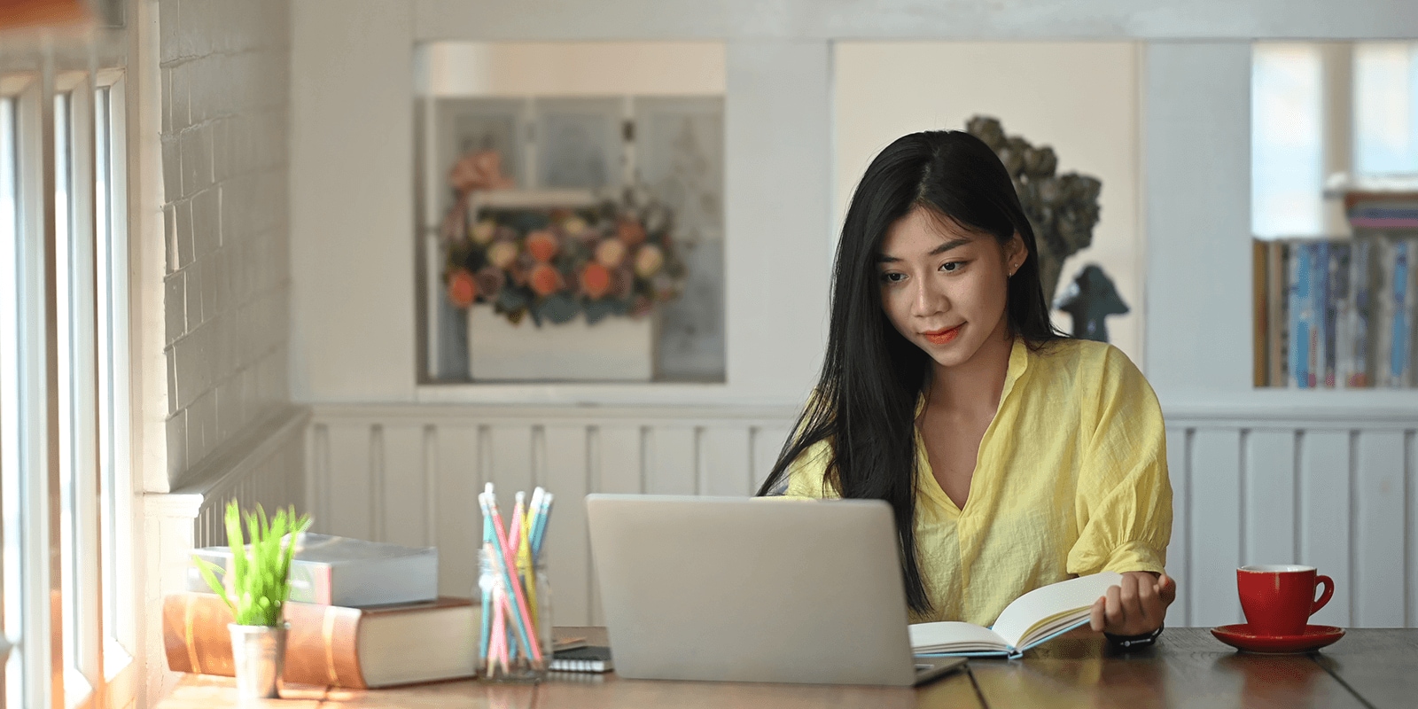 Student looking at laptop holding a notebook.