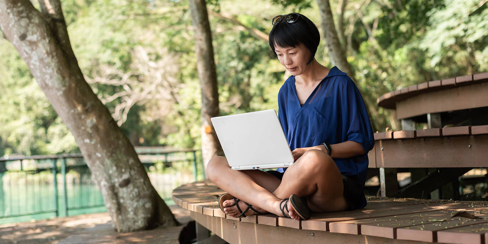 A woman working on a laptop sitting on a bench outside