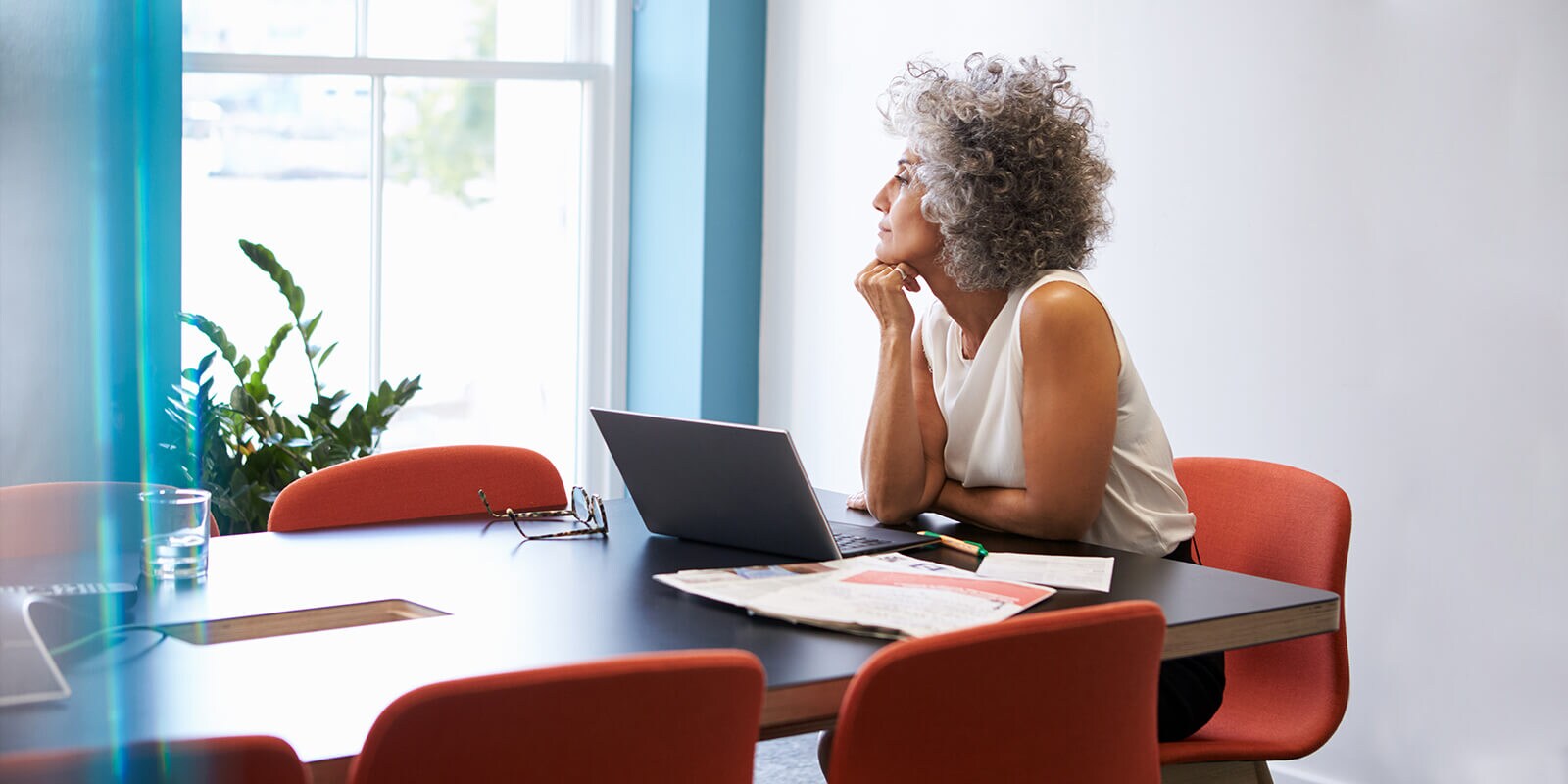 Instructor looking out the window, with papers and laptop computer in front of them