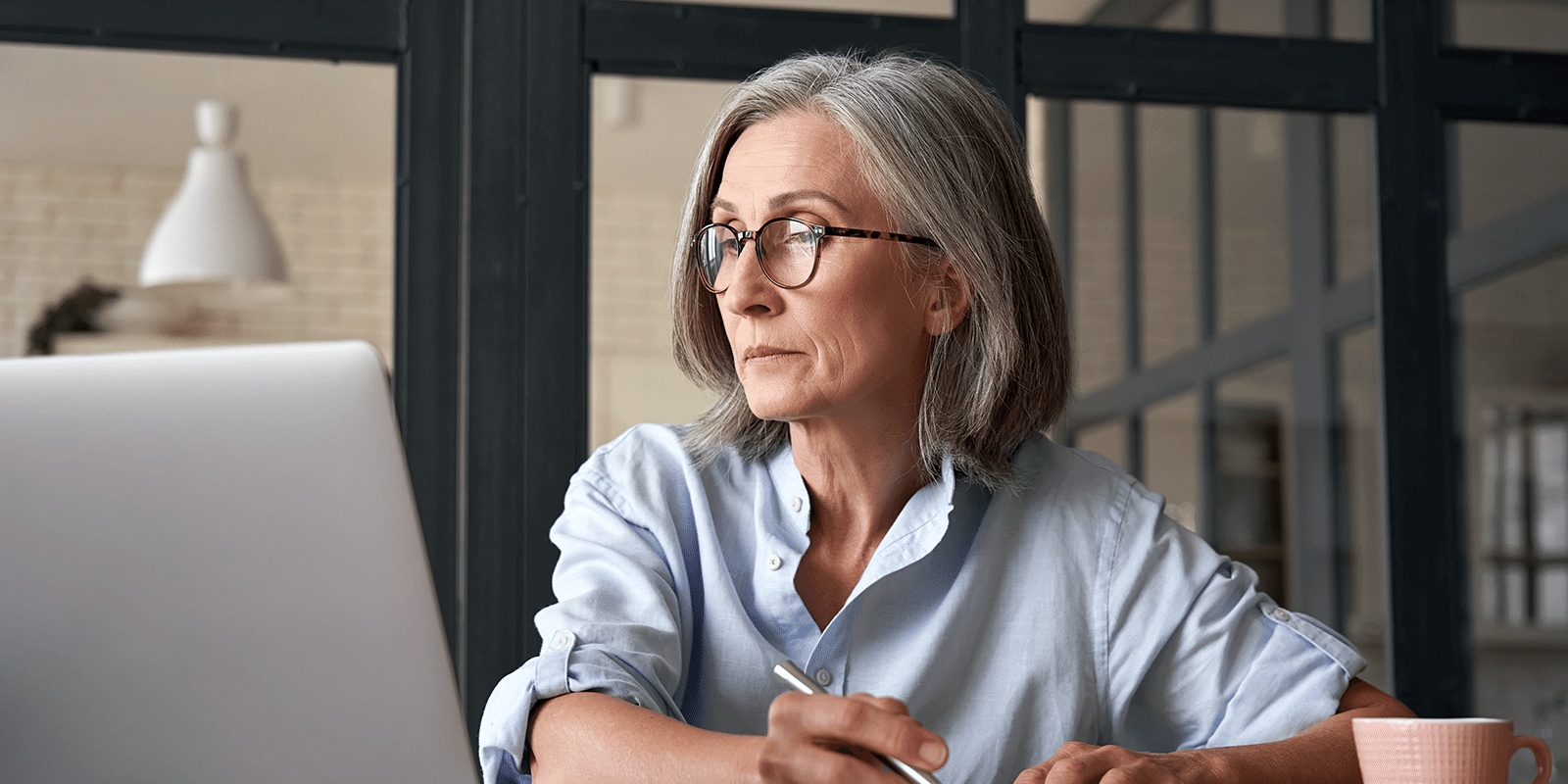 a woman looking at a computer and taking notes