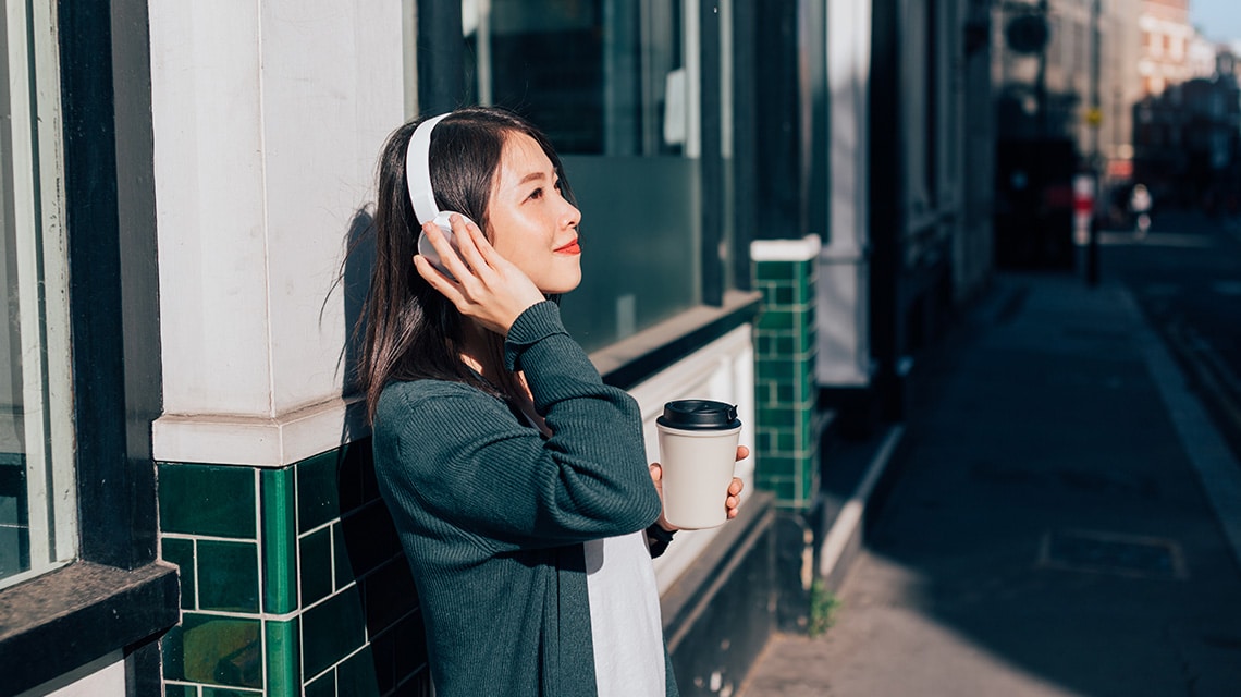 Young woman listening to music through overhead head phones