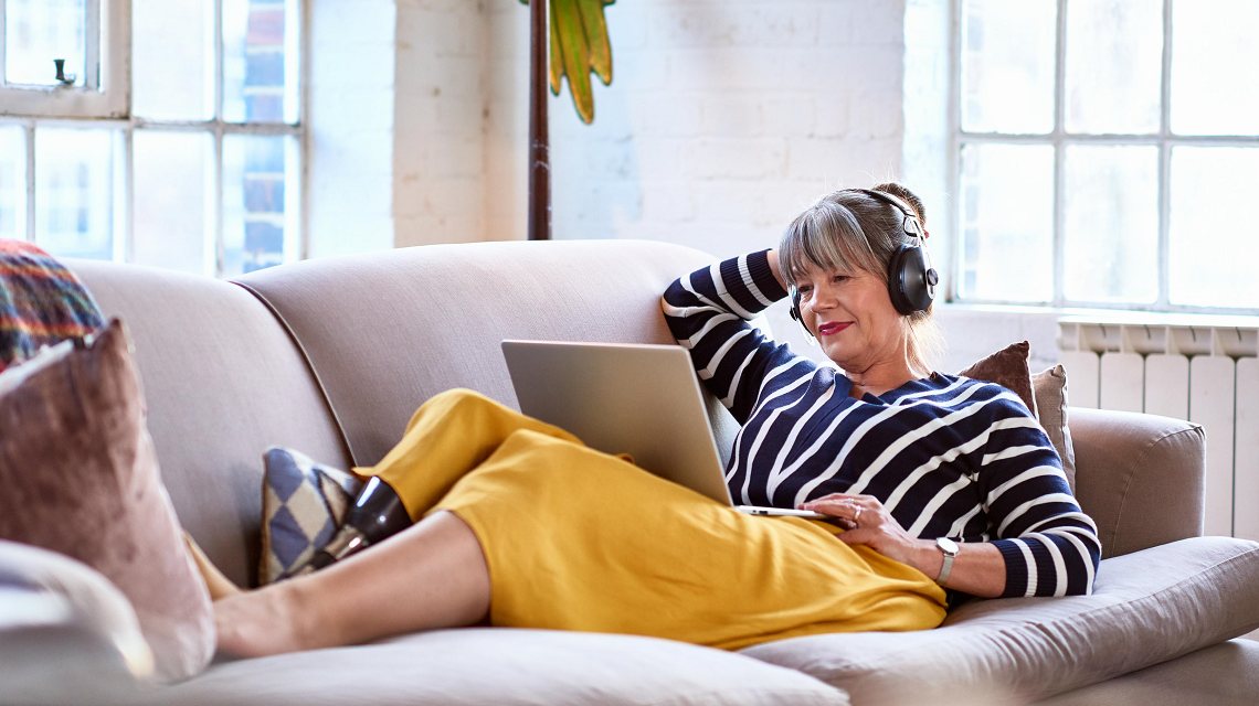 Image of a woman watching a webinar from a sofa