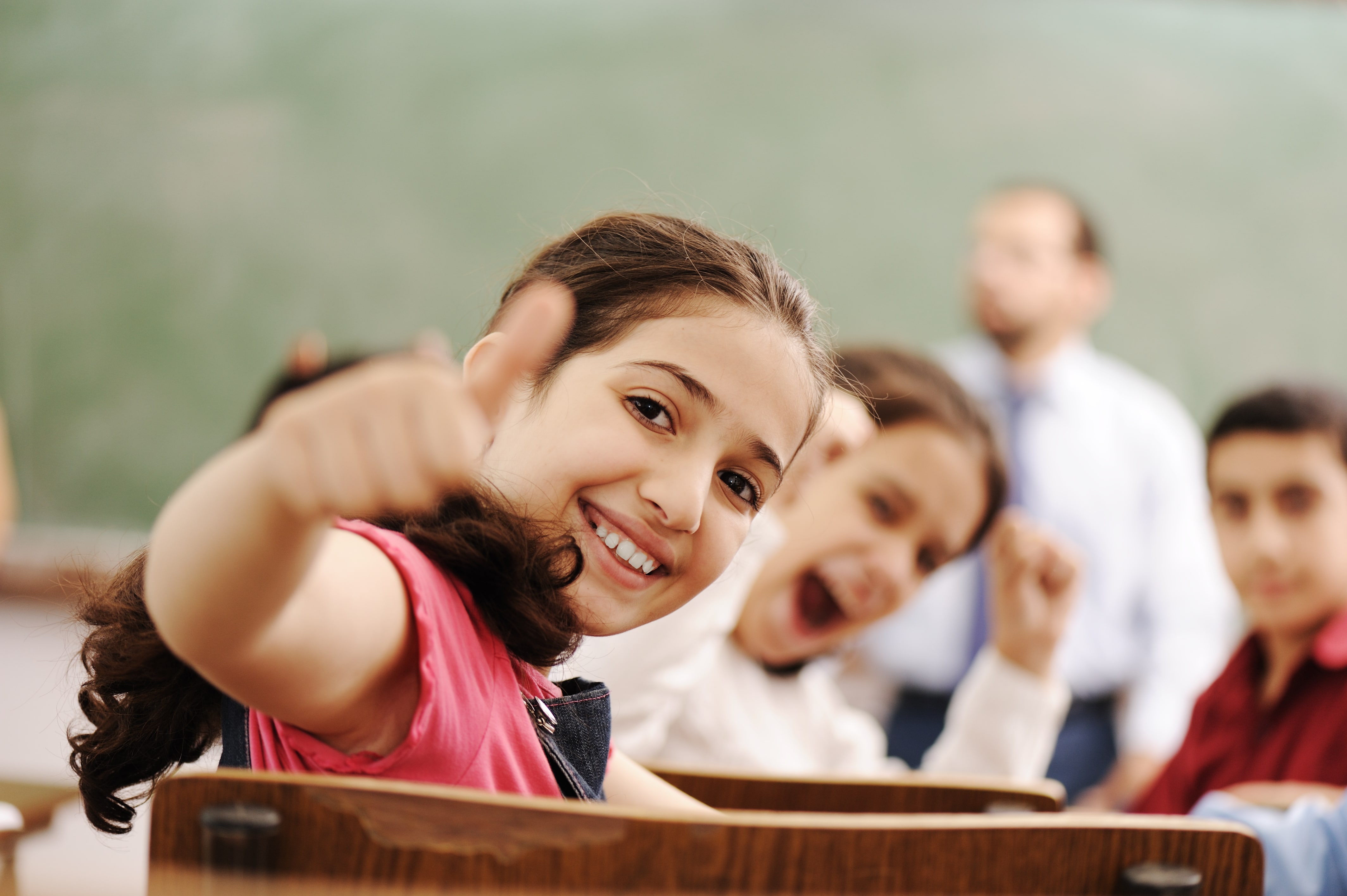 Girl in classroom giving thumbs up