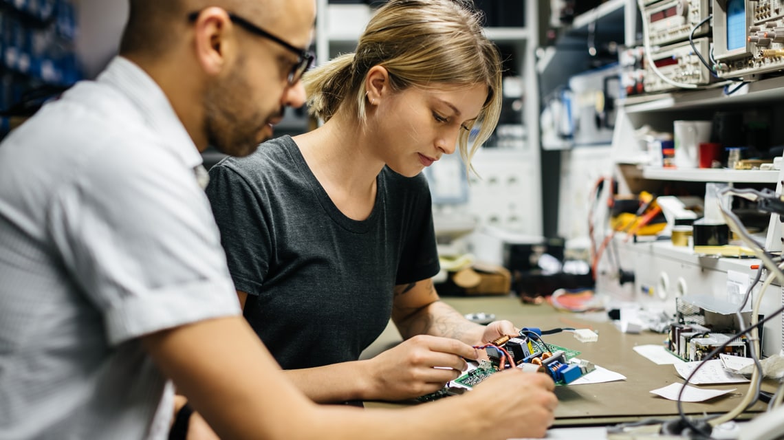 An image of an apprentice and her tutor working through a PCB board