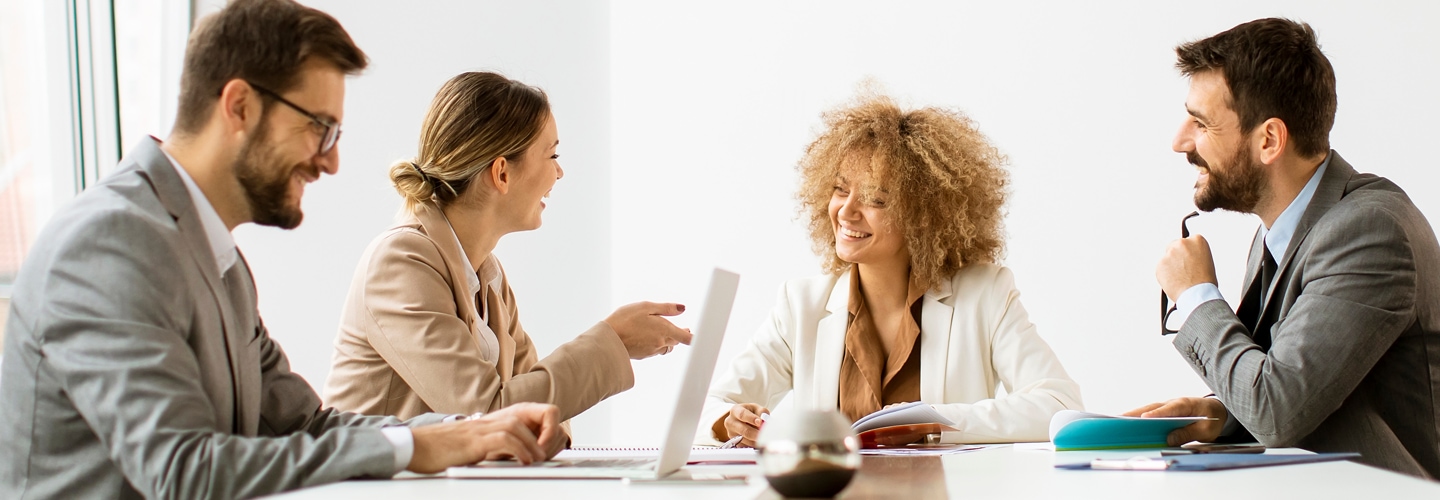 Coworkers sat at a table together, talking and smiling