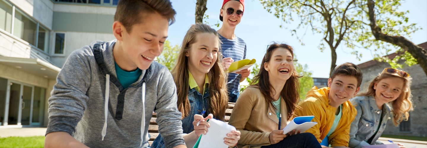 A group of students sat together smiling outside