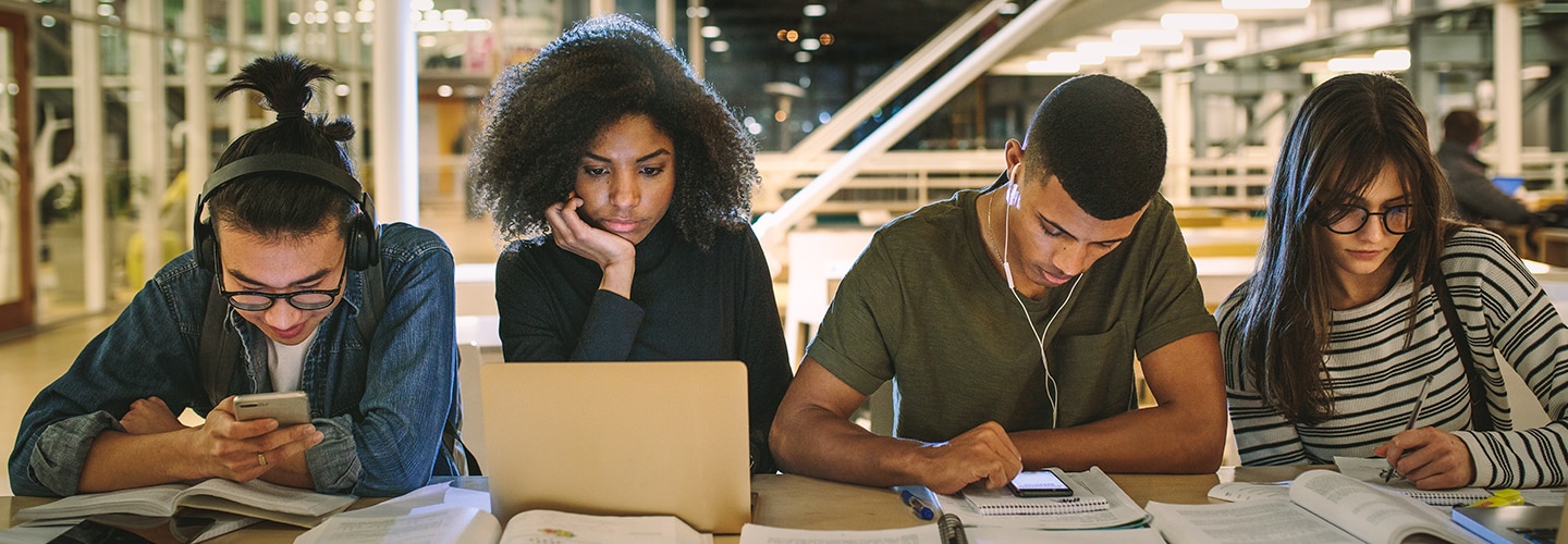 A group of university students sat in a library together studying