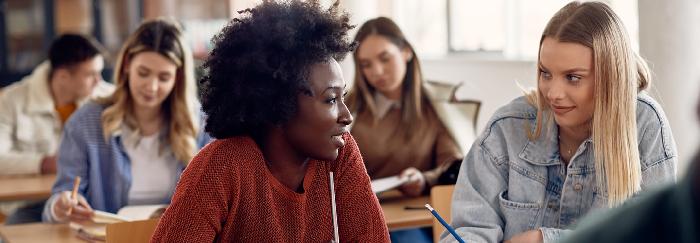 Two women sat together in a university classroom talking