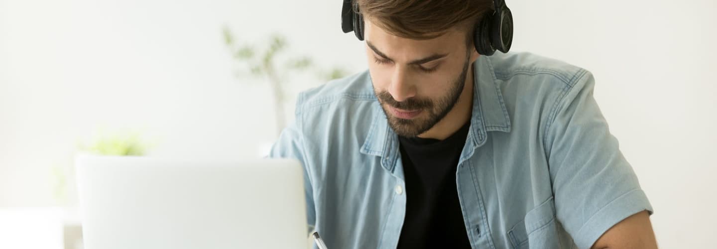 جلس رجل على جهاز كمبيوتر محمول مع سماعات الرأس