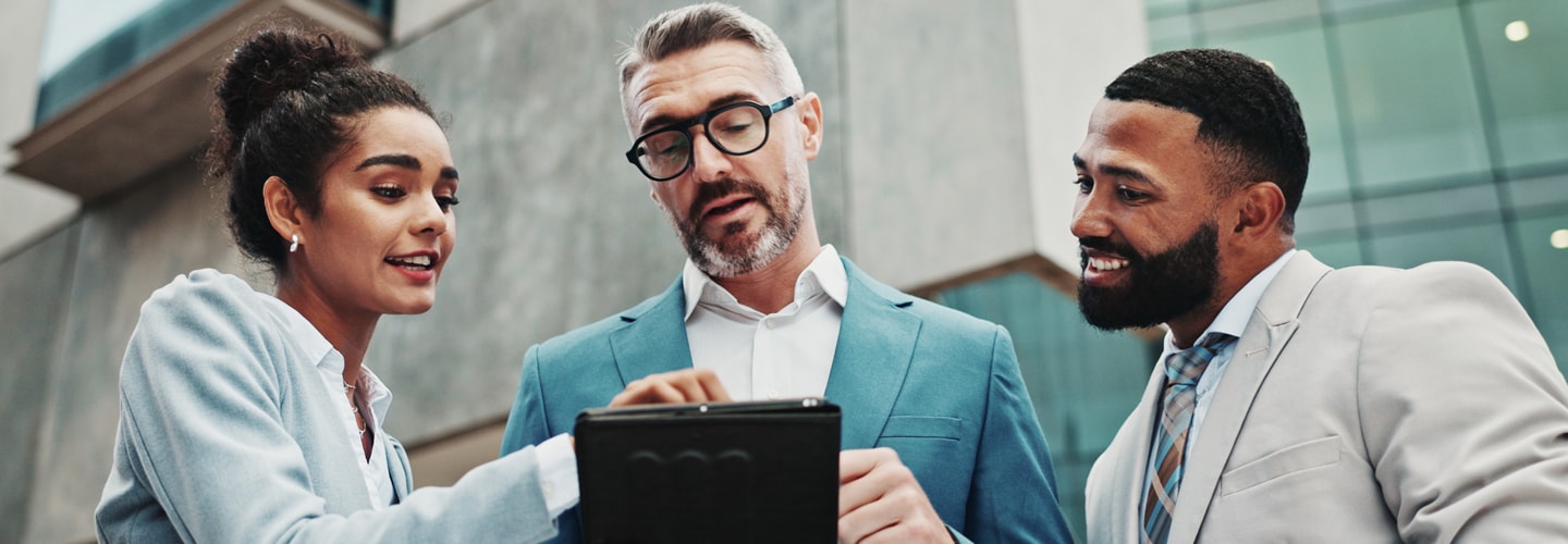 Agents stood outside looking at a tablet smiling