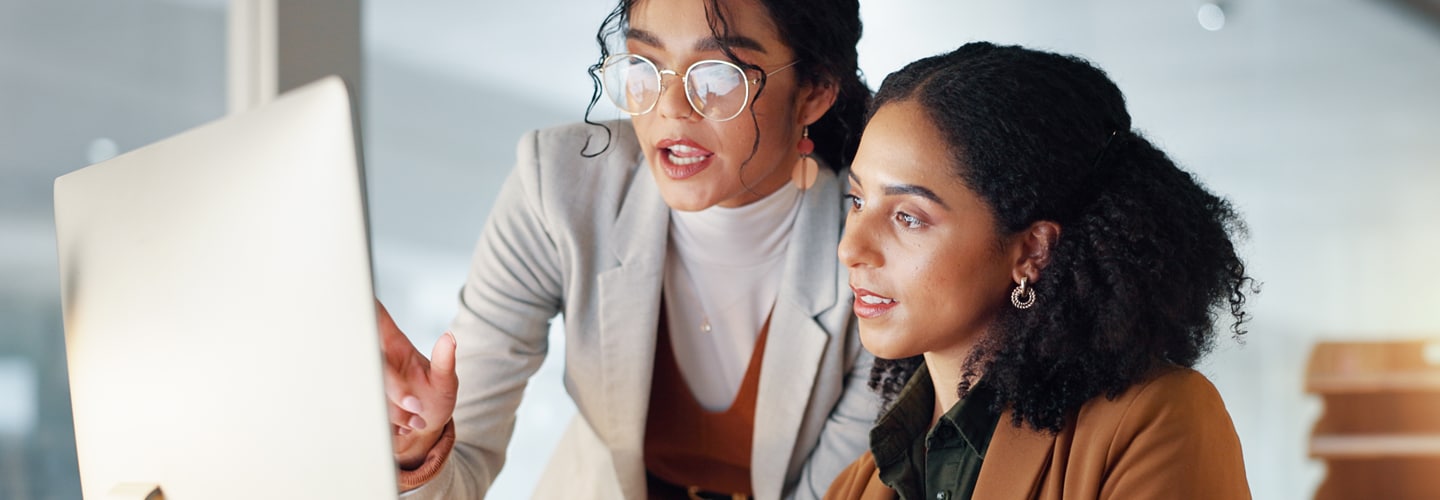 Two business women talking together at a computer