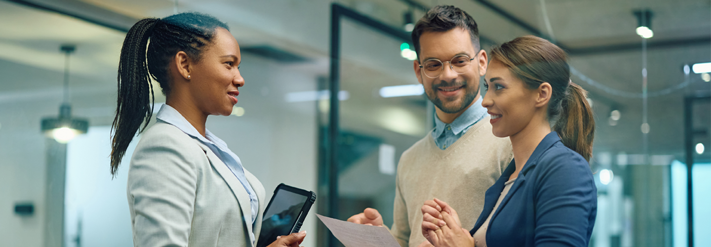 Coworkers talking together in an office by windows
