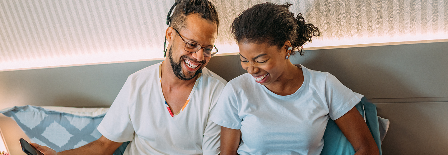 Two people sat togther with phones smiling