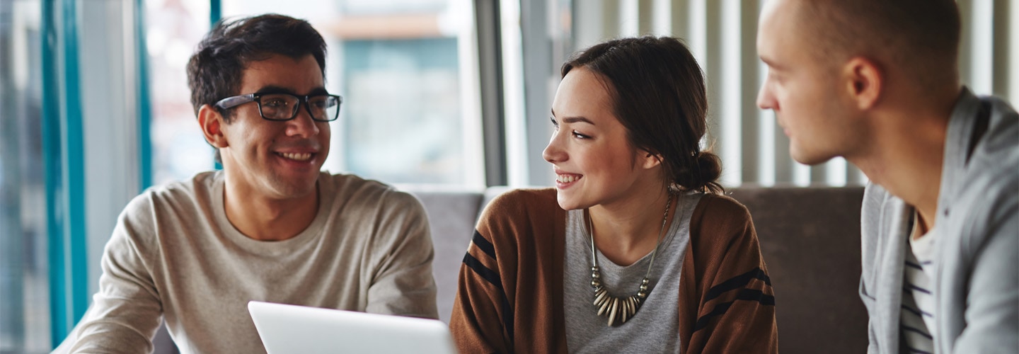 أصدقاء يدردشون حول جهاز كمبيوتر محمول