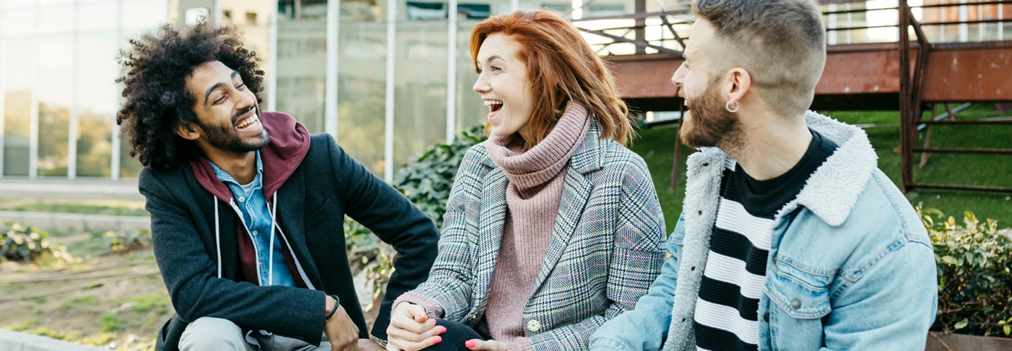 A group of friends sat outside smiling and talking