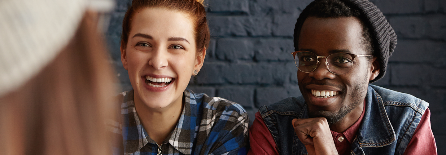 Two friends smiling at a person in front of them