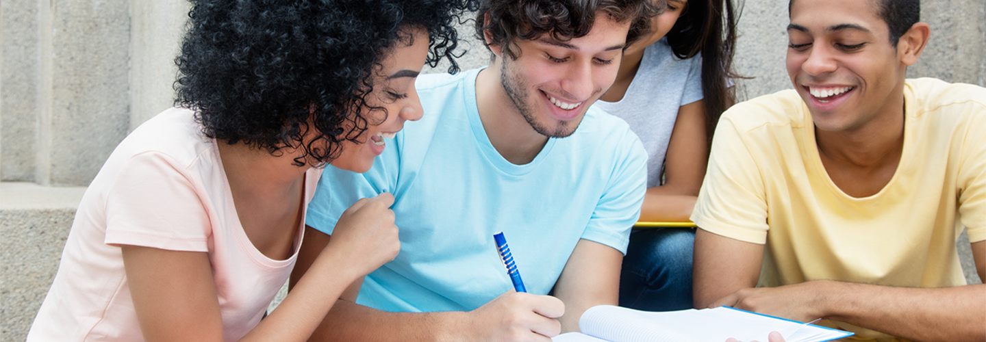 a group of friends smiling and looking at the one who is writing in a notepad
