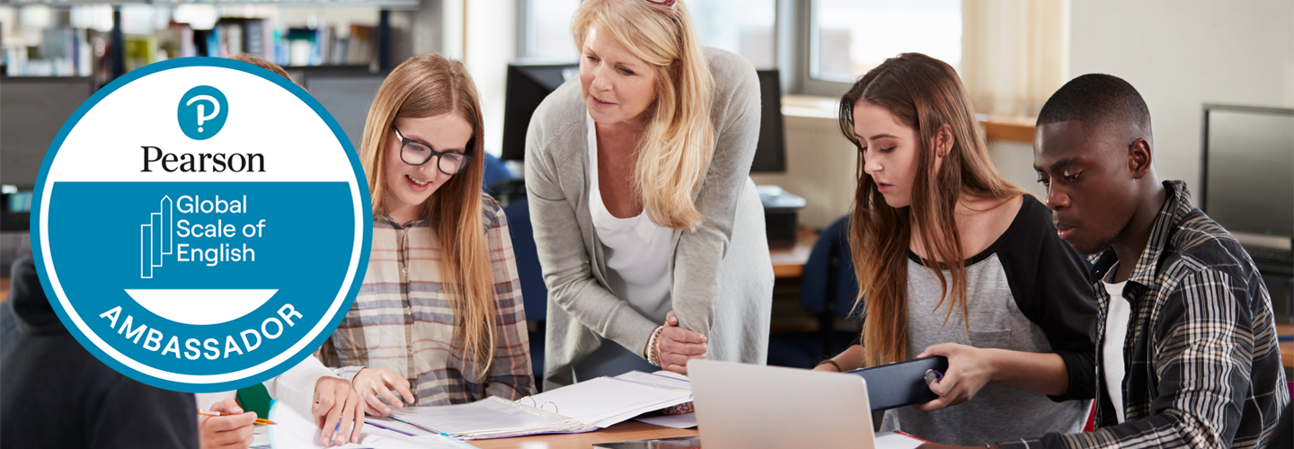 جلس الطلاب على طاولة مع معلم يقف معهم يتفاعل معهم